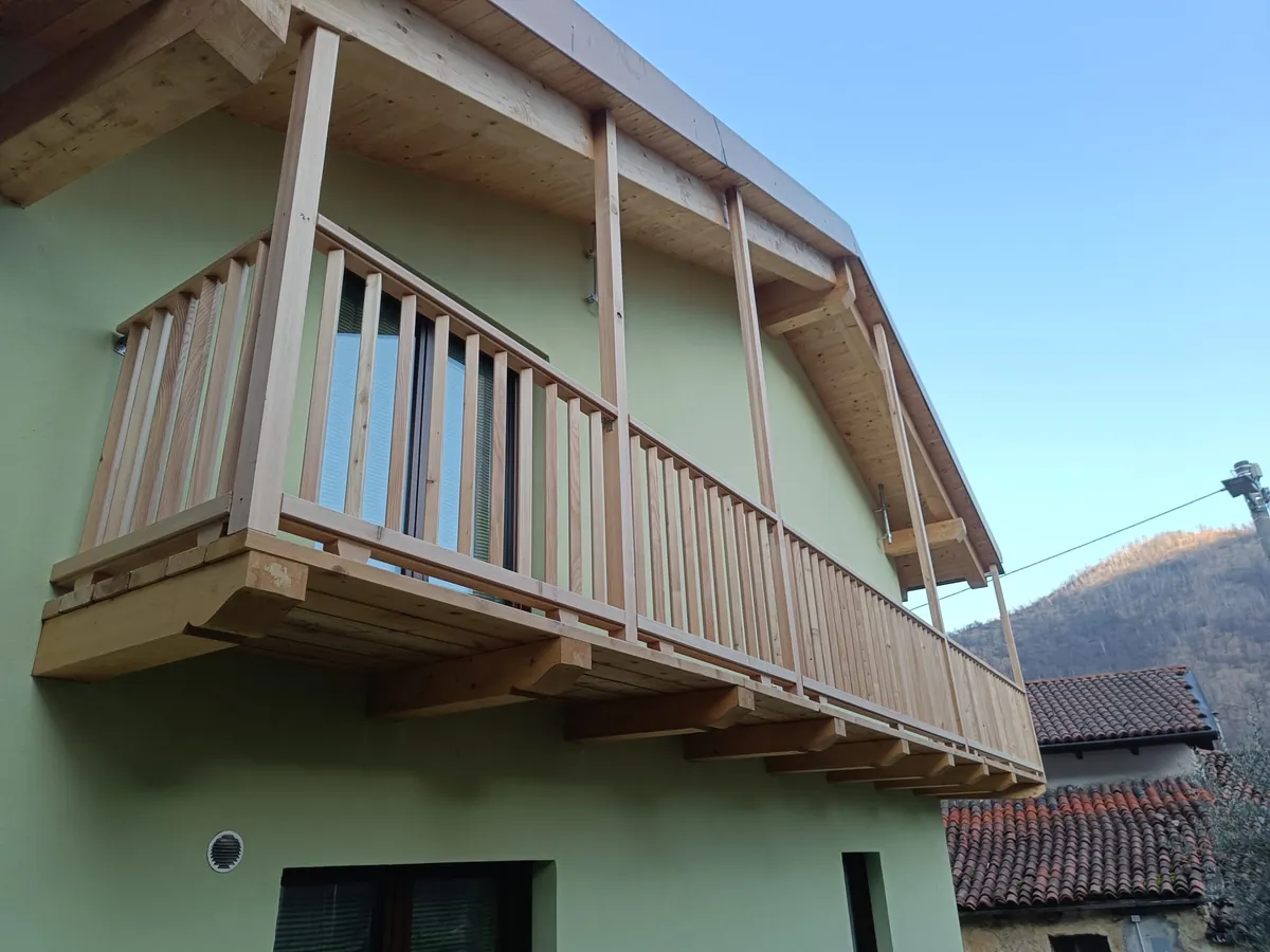Una casa con la facciata tinteggiata in verde e un balcone in legno